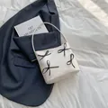 Grande borsa tote bianca con fiocchi neri su giacca grigia con un libro di moda - Bianco Sporco