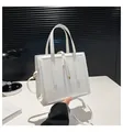 Detailed shot of white tote bag with glossy leather texture and gold metal accents - White