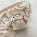 Chic beige crossbody bucket bag with decorative silk scarf and plush charm detail - With Pendant / White