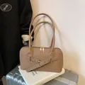 Khaki pillow shoulder bag featuring woven texture and gold hardware on a book - Brown