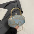 Lichtblauwe bolvormige clutch met goud borduurwerk en metalen handvat design - Blauw