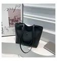 Detail of minimalist black matte leather tote bag placed on a white artistic display stand - Black