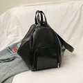 Matte black geometric PU leather backpack with silver zippers on a white fabric background - Black