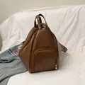 Dark brown matte PU leather backpack featuring a geometric fold design and front pocket - Brown