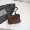 Sac fourre-tout marron foncé en cuir mat avec poche avant et bandoulière sur table - Marron
