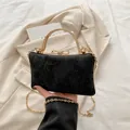 Elegant black evening bag with gold handle and butterfly buckle on beige blazer - Black
