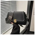 Close-up of black lychee grain leather bag with geometric pattern wide strap and gold buckle - Black