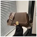 Detail of dark brown lychee grain leather handbag with gold snap and geometric strap - Brown