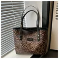 Detailansicht der Leopard-Tragetasche mit schwarzen Lederriemen und goldenen Metallnieten - Kaffeebraun