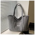 Detail of grey corduroy tote bag featuring an outer pocket and white textile label - Gray