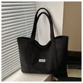 Detailed texture of black corduroy tote bag featuring a white Fashion Instinct label - Black