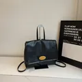 Detail of minimalist black PU leather backpack with gold oval buckle on a marble surface - Black
