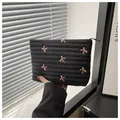 Macro detail of quilted black nylon makeup bag with pink embroidered bows and zipper - Black
