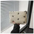 Detail of quilted cream makeup bag featuring elegant black bow embroidery and zipper - White