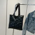 Modern black quilted puffer tote bag with glossy wave stitching and wide shoulder straps - Black