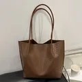 Retro braune Tragetasche mit Krokodilstruktur und langen Schultergurten auf Stuhl - Braun