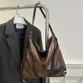 Bolso tote marrón oscuro mate con detalle de cremallera lateral en una percha - Marrón