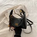 Bolso media luna negro chic con logo dorado y amuleto decorativo de rayas tejidas - Con Colgante / Negro