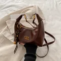 Bolso medialuna retro marrón oscuro con herrajes dorados y detalle de borla flecada - Con Colgante / café