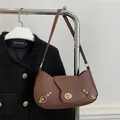 Borsa a mezzaluna marrone scuro in pelle liscia con chiusura girevole dorata e dettagli - Marrone
