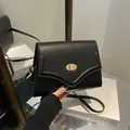 Borsa sottobraccio minimalista in pelle nera con chiusura girevole dorata e tracolla sottile - Nero