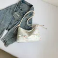Sac bandoulière en jacquard blanc avec broderie colorée et nœuds sur fond blanc épuré - Blanc