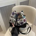Floral canvas bucket bag with black leather accents and golden zipper hardware - Black