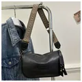 Detail of black cylindrical shoulder bag with geometric patterned wide strap and retro texture - Black