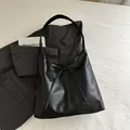 Minimalist black leather tote bag with stylish bow tie lacing and shoulder strap design - Black