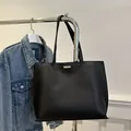 Minimalist black tote bag in matte leather with metallic trim and long shoulder strap - Black
