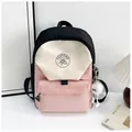 Primer plano de una mochila de nailon tricolor con colgante de peluche y logotipo frontal - Bolso Individual / Rosa / S