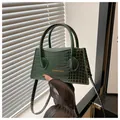 Detail van bosgroene mini-handtas met krokodillenreliëf, gouden letters en stevige handvatten - Groen