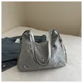 Macro shot of silver textured shoulder bag featuring metallic butterfly charms and chain details - Silver