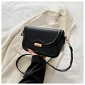 Detailed close-up of compact black leather crossbody bag with cylindrical gold metal lock - Black