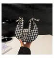 Nahaufnahme der schwarz-weißen Hahnentritt-Handtasche mit goldener Wellenschnalle - Hahnentritt-Stil