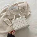 Sac bandoulière matelassé blanc avec broderie cœur et poignée sur un blazer beige - Blanc