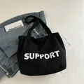 Borsa tote in tela nera con stampa SUPPORT e design a tracolla spazioso e minimalista - Nero
