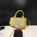 Goldene Handtasche mit Krokodilmuster, Metall-Finish und silbernem M-Logo-Anhänger - Gold