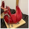 Red pleated leather crescent bag featuring a stylish silver beaded bow pendant - Red