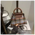 Detailed view of vintage plaid handbag with resin handle and leather flap on books - Brown
