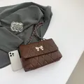 Deep brown quilted crossbody bag featuring a golden bow buckle and chain strap - Brown