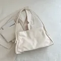 Minimalist cream white leather tote bag featuring debossed lettering and knotted shoulder strap - White