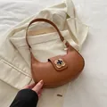 Vintage brown leather crescent hobo bag with a gold clover clasp on a textured blazer - Brown