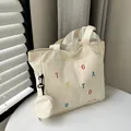 Off-white canvas tote bag featuring colorful letter embroidery and a small round coin purse - Off White