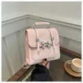 Mini sac à dos rose avec noeud papillon argenté et texture cuir mat sur bureau - Rose