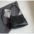 Bolso tote minimalista de cuero PU negro con cordón anudado sobre un traje gris - Negro
