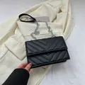 Classic black chevron quilted crossbody bag with silver chain strap on suit jacket - Black