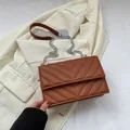 Caramel brown V-quilted crossbody bag with silver chain strap on beige blazer - Brown