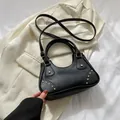 Classic black leather handbag with gold rivets on beige blazer, stylish crossbody style - Black