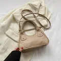Minimalist apricot handbag with golden studs and a slim strap in a lifestyle setting - Khaki